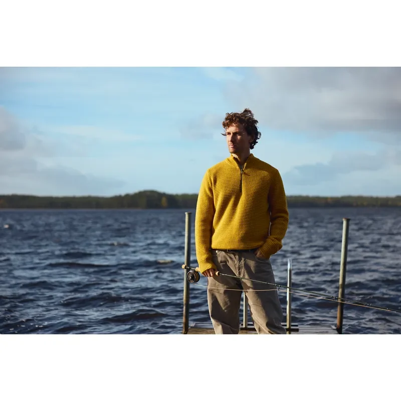 Herr im gelben Strickpullover am See