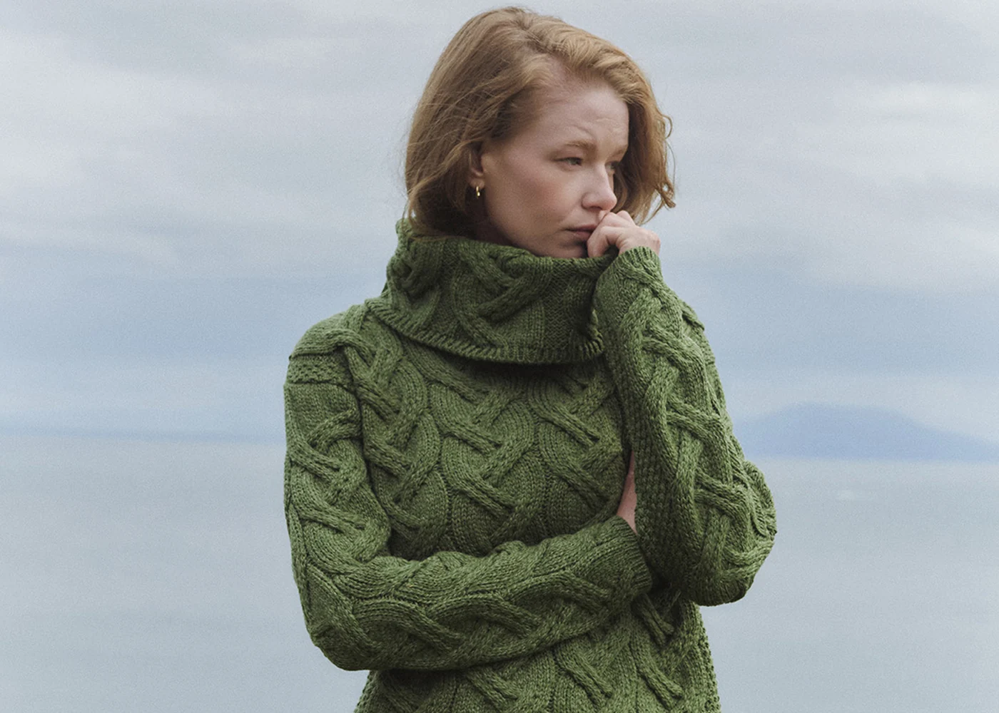 Dame im grünen Aran-Strickpullover an der irischen Küste