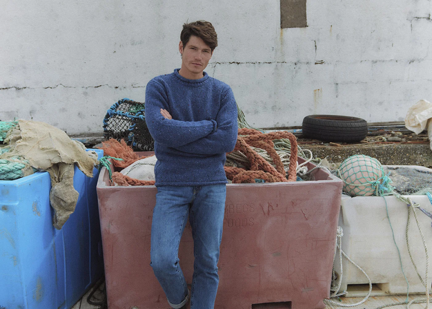 Herr im hellen Aran-Strickpullover in grüner Küstenlandschaft