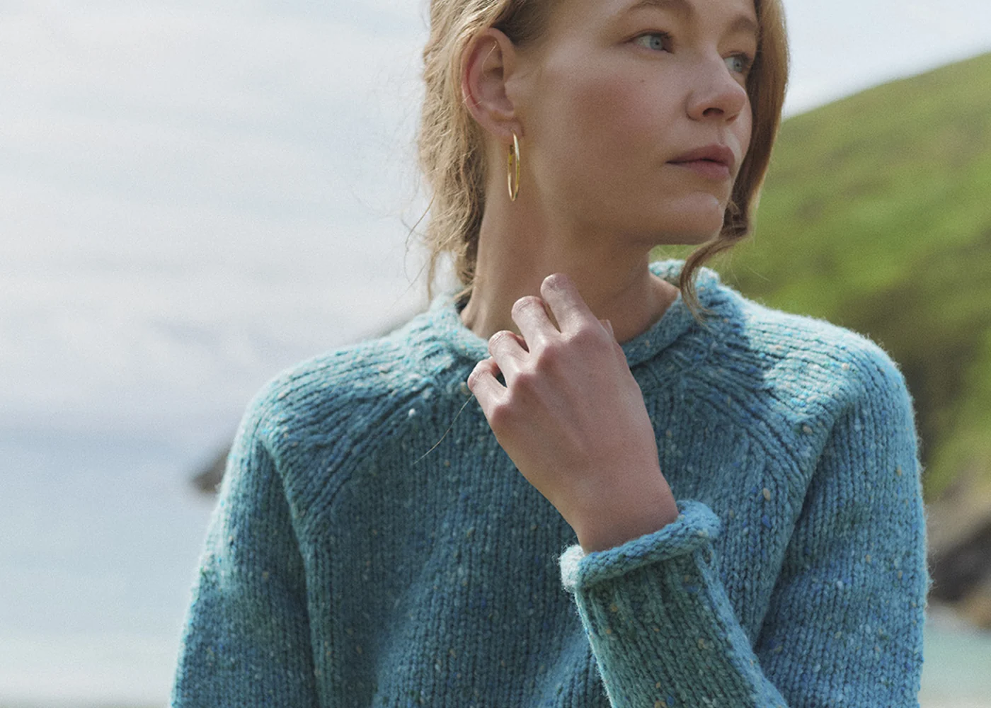 Dame im türkisfarbenen Aran-Wollpullover am Meer